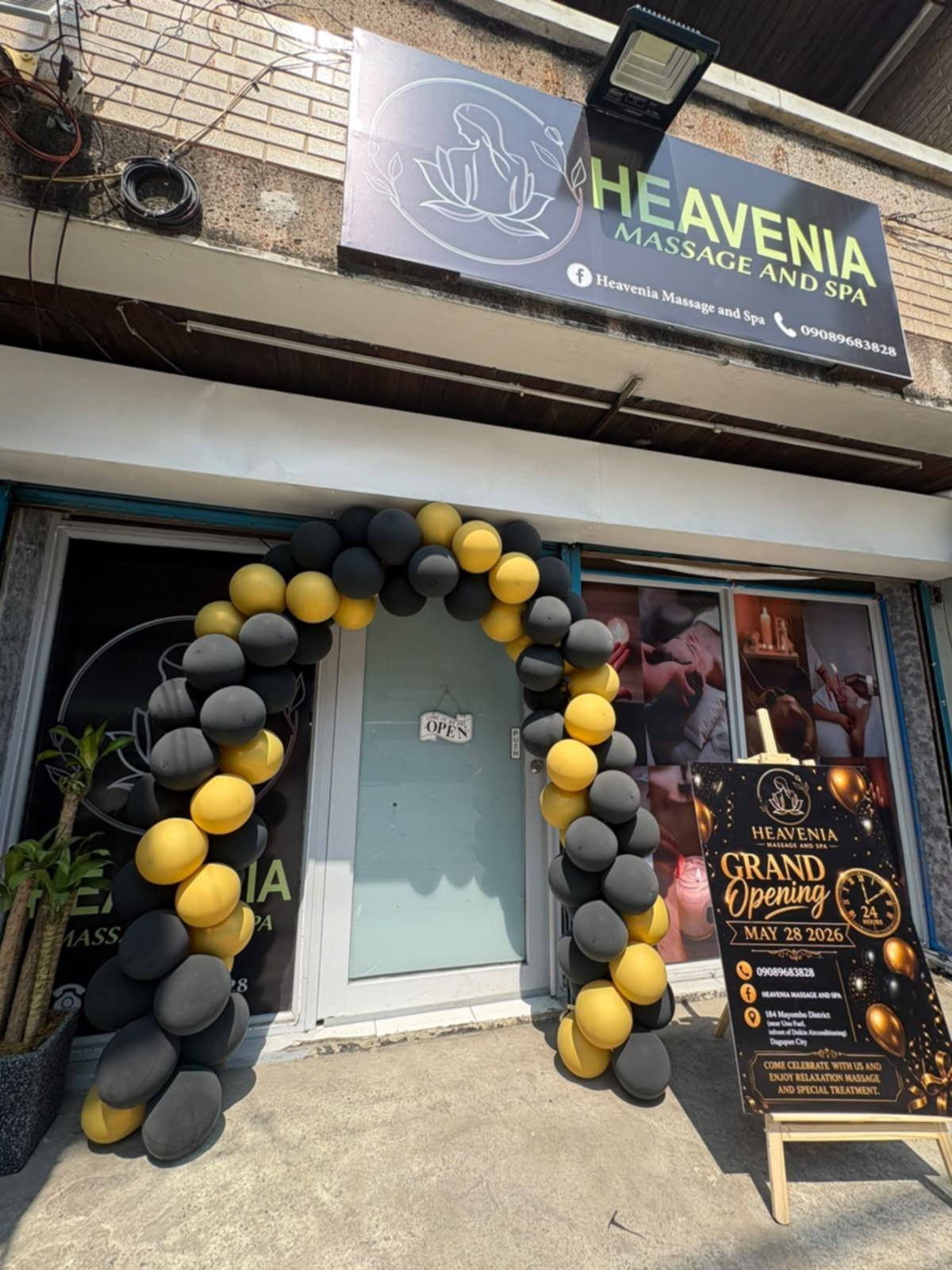 Heavenia Massage and Spa storefront with its sign and black and gold balloon arch